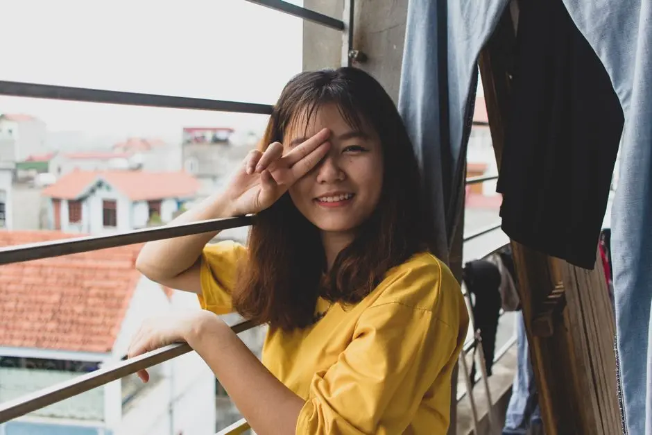 Wanita muda tersenyum sambil melakukan peregangan di balkon rumahnya